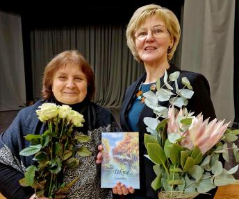 Aly­taus ap­skri­ties li­te­ra­tų klu­bo „Tėk­mė“ pir­mi­nin­kė Re­gi­na Ra­si­mie­nė sveikina al­ma­na­cho su­da­ry­to­ją Scho­las­ti­ką Ka­va­liaus­kie­nę. 